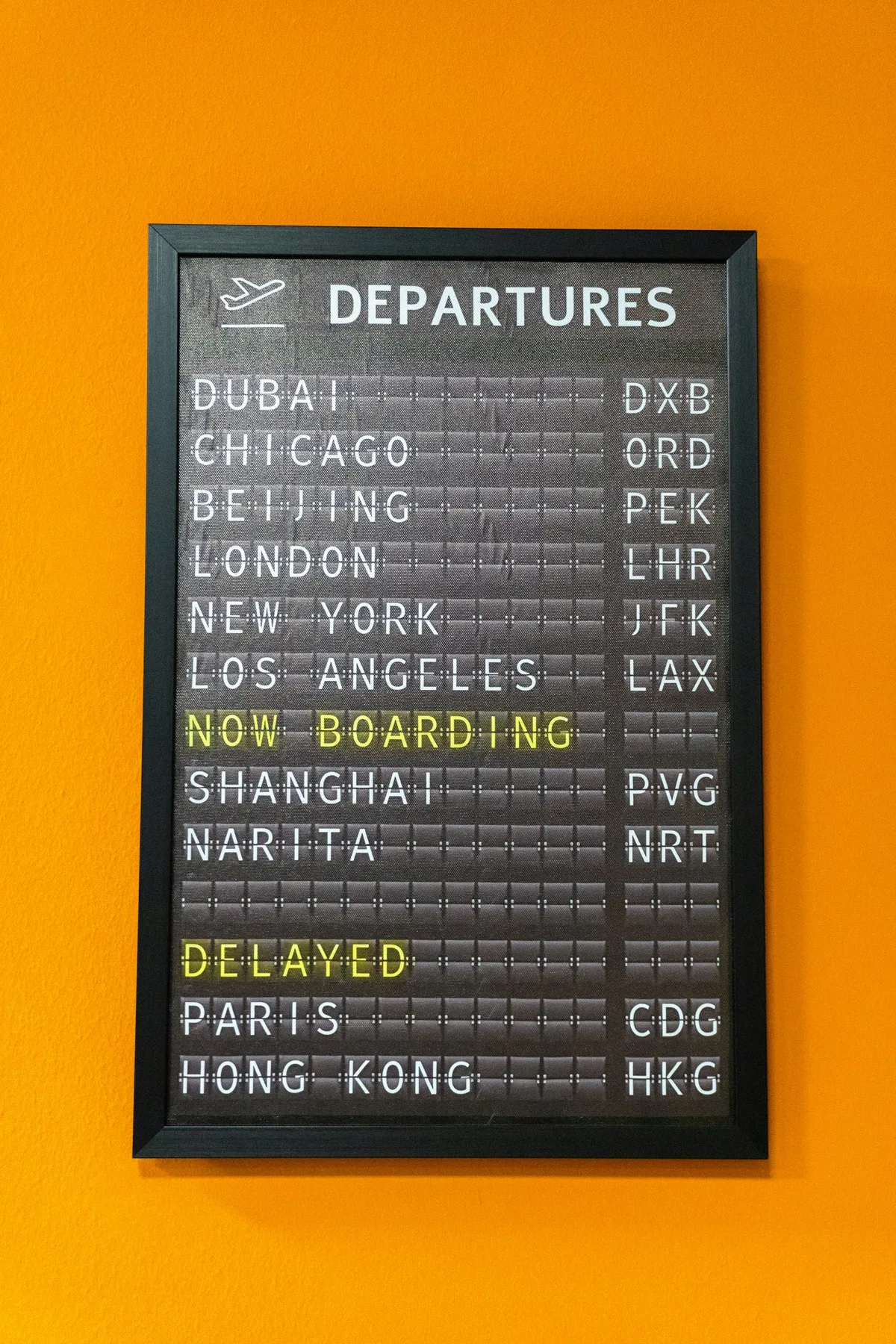 An airport departures board showing flights, with one flight marked NOW BOARDING and another marked DELAYED.
