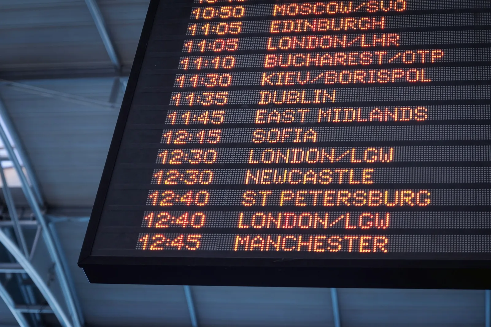 An airport departure board listing flight times and destinations, the kind of screen travelers watch while deciding whether to cancel a new booking.