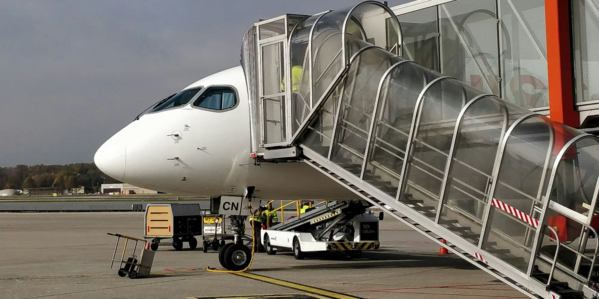 Passengers boarding an aircraft at an airport gate, carry-on bags in hand