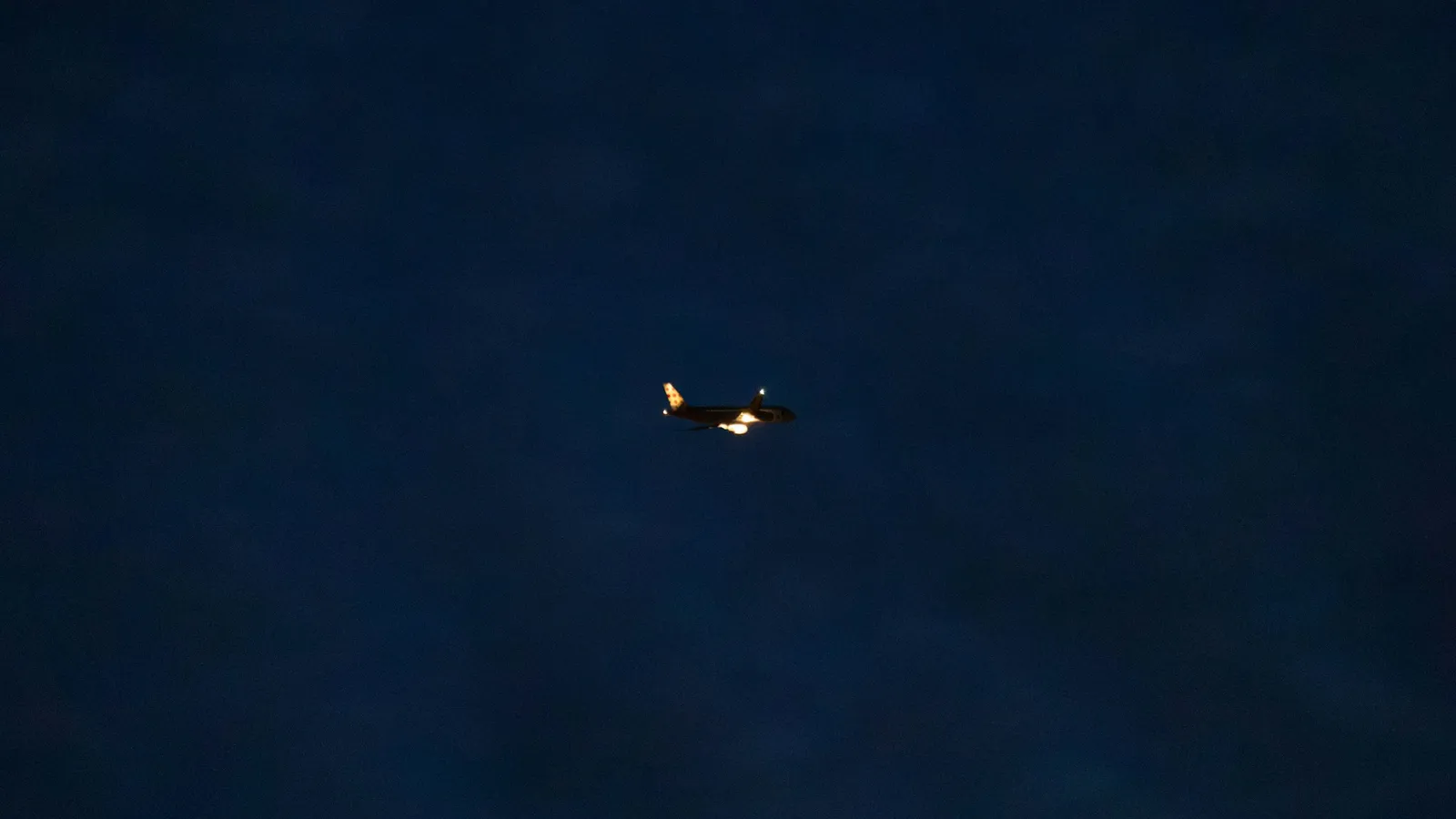 A commercial airplane in flight against a dark blue night sky